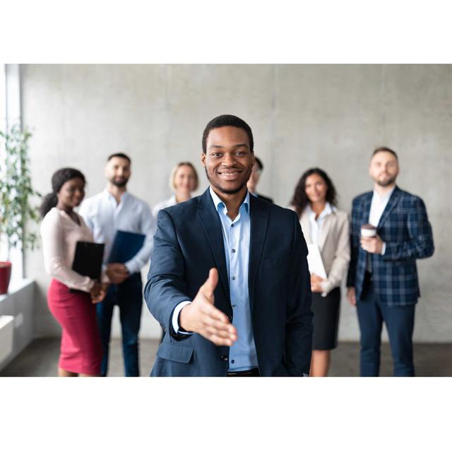 Smiling man standing with outstretched hand for a handshake.