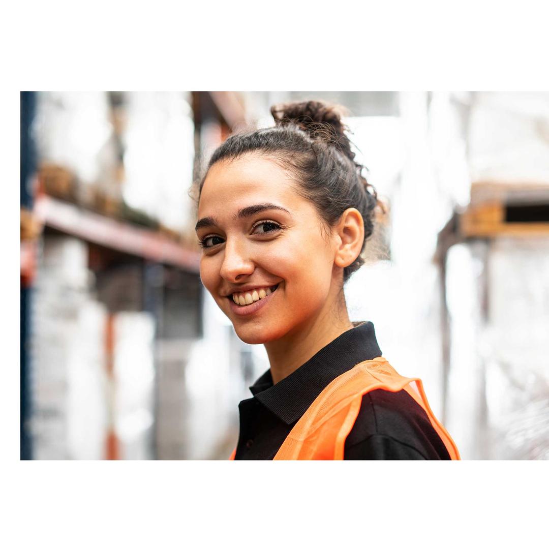 A woman smiling in a warehouse setting.