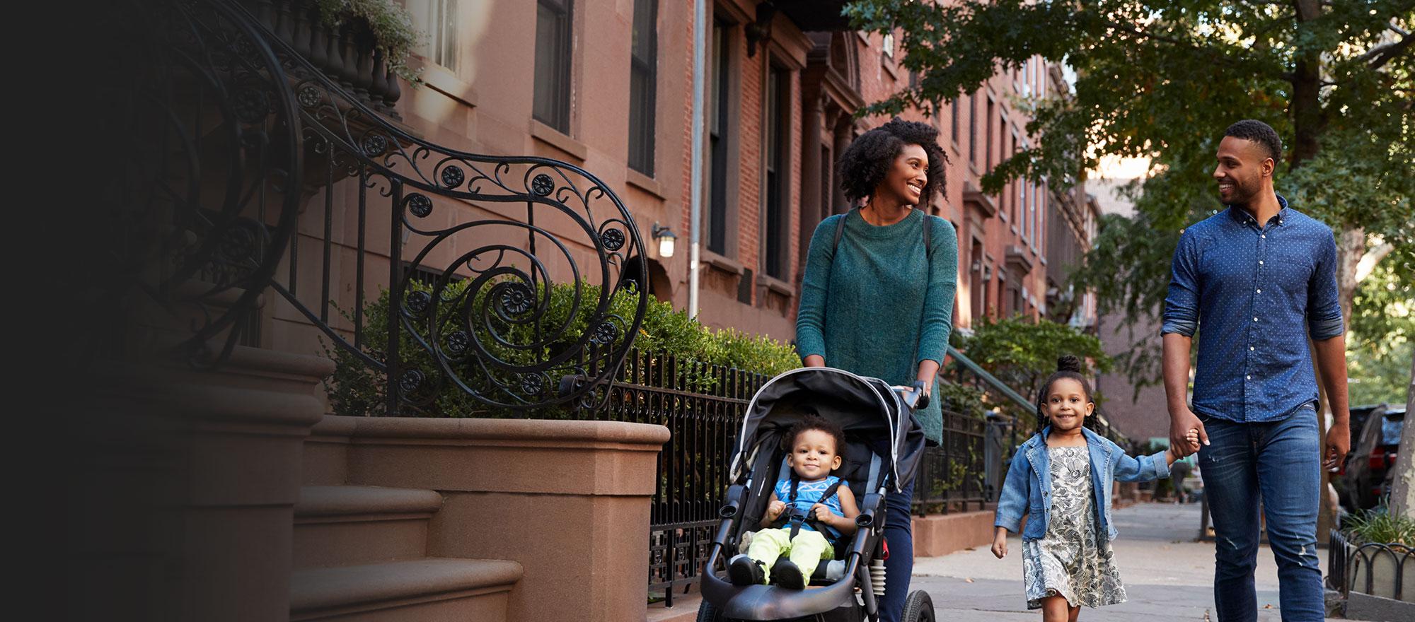 A mobile optimized image of a happy family safely walking down the street in their community.