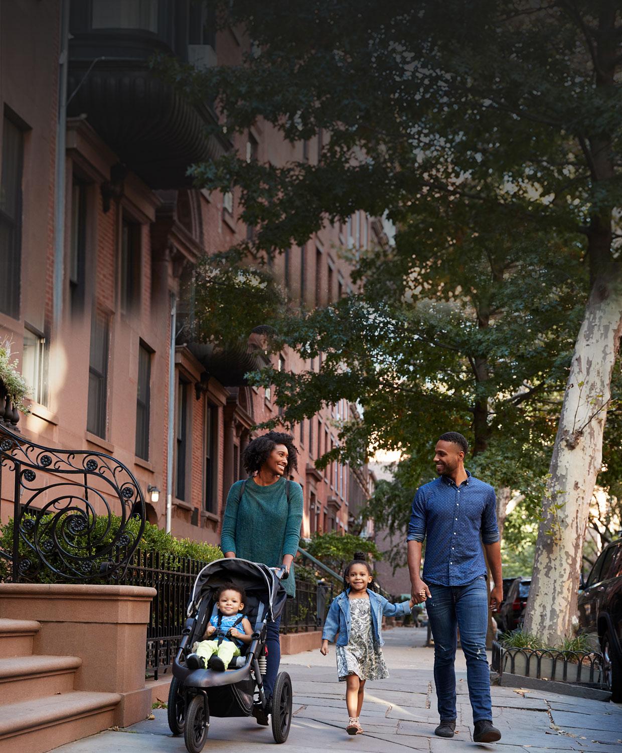 A mobile optimized image of a happy family safely walking down the street in their community.